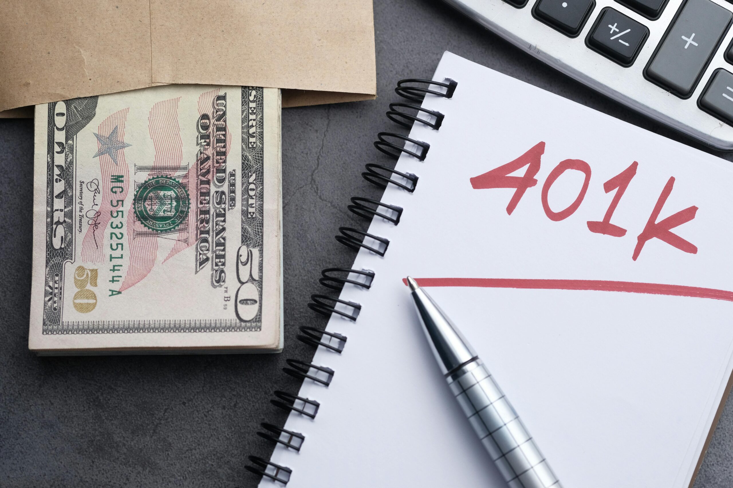 Stack of cash and a notebook with the word "401K" written in marker.